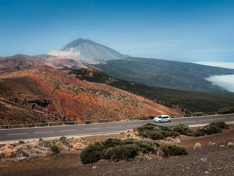 Stunning view of Mount Teide in Tenerife with a car on a scenic road, under clear skies.