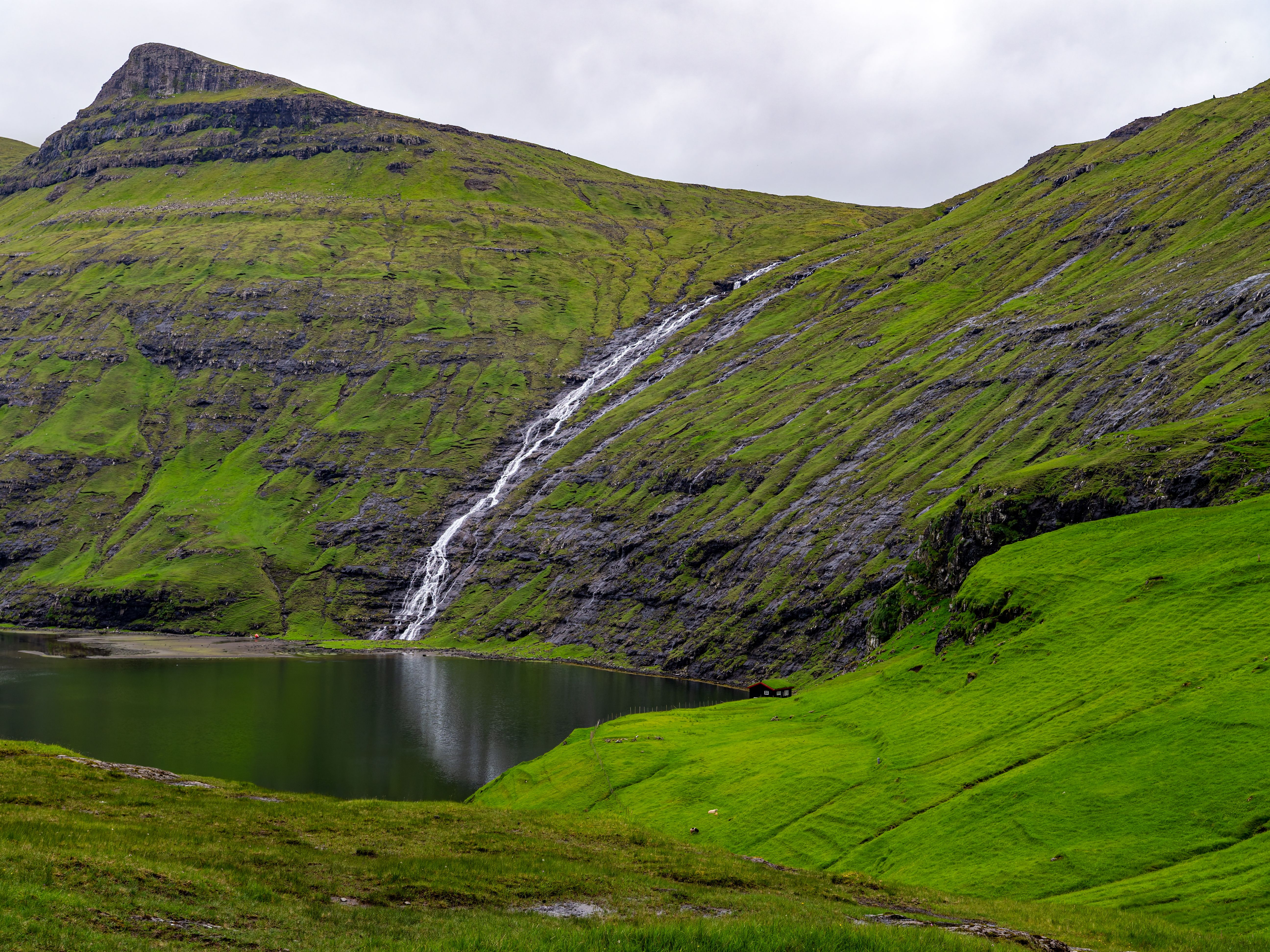 Beautiful waterfall cascading down a lush, green hillside into a serene lake.