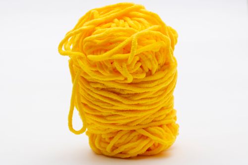Free A vibrant yellow yarn ball set against a simple white background, perfect for crafting projects. Stock Photo