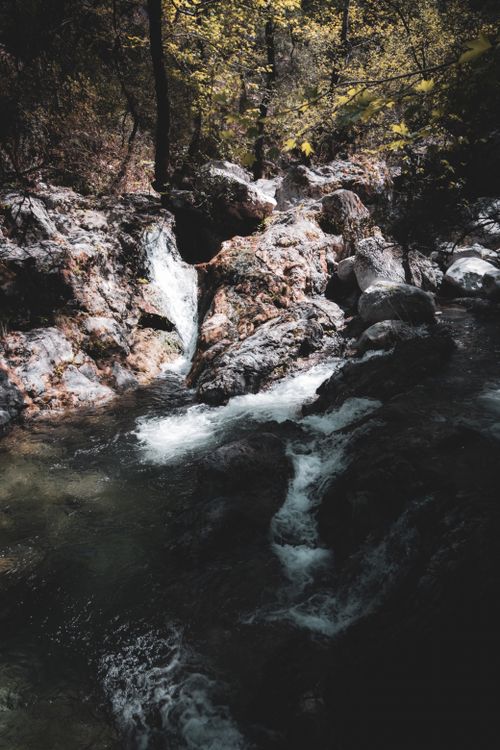 Free Serene waterfall cascading through rocky forest landscape in autumn. Stock Photo