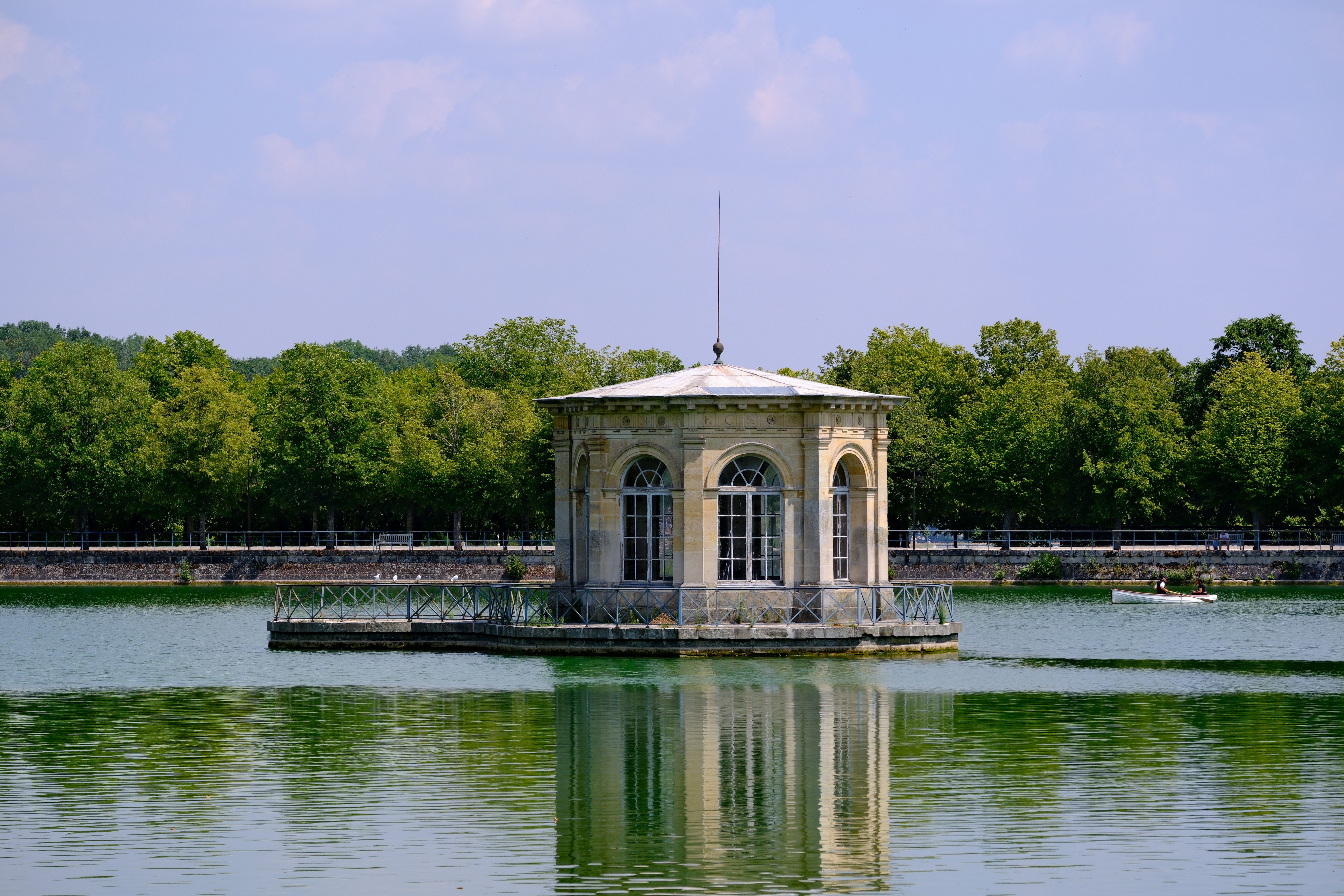 Serene pavilion surrounded by lush greenery and clear waters at Fontainebleau, a scenic spot in France.