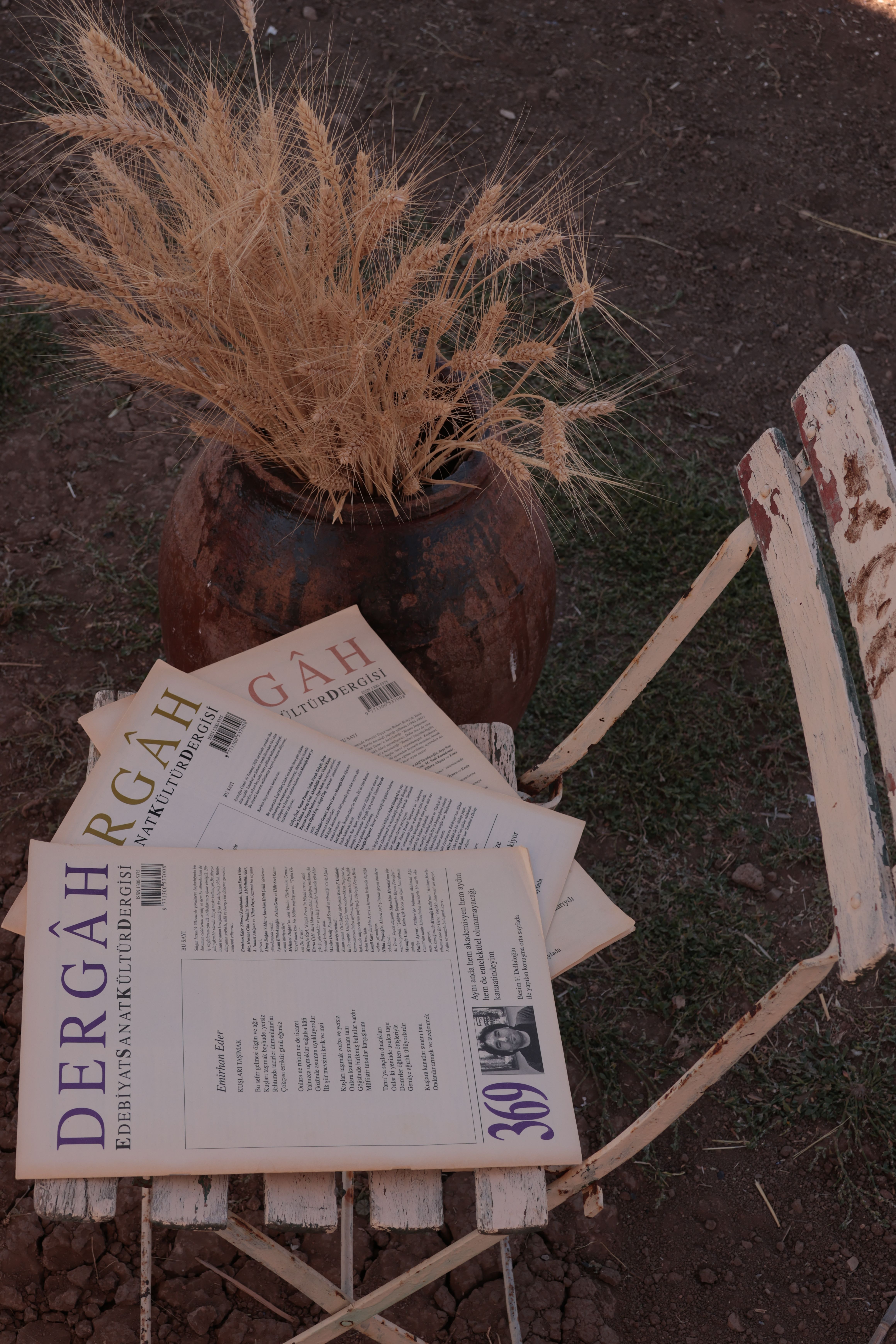 A rustic setup featuring magazines and wheat in a clay pot.