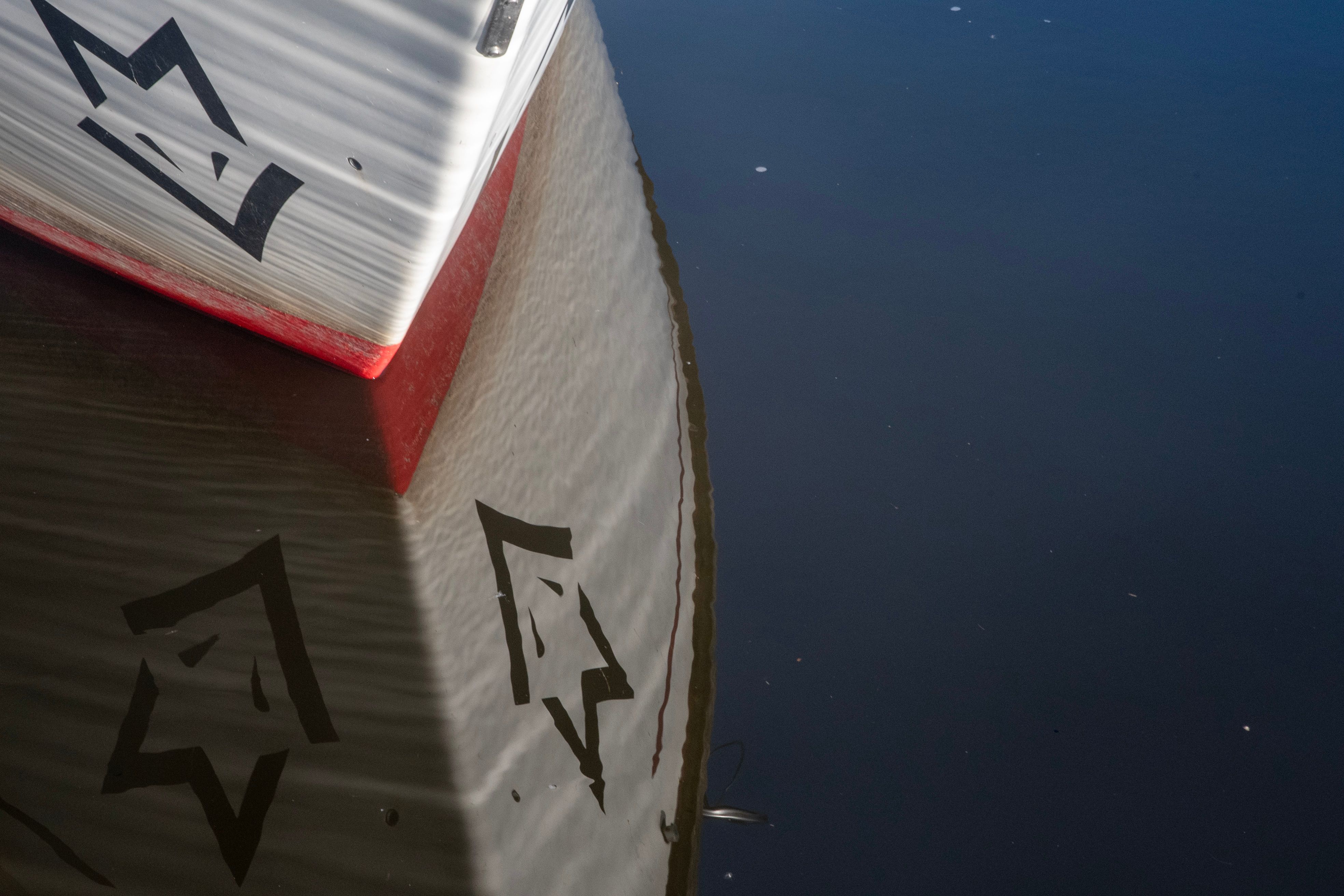 Close-up of a boat's reflection with abstract patterns on calm water.