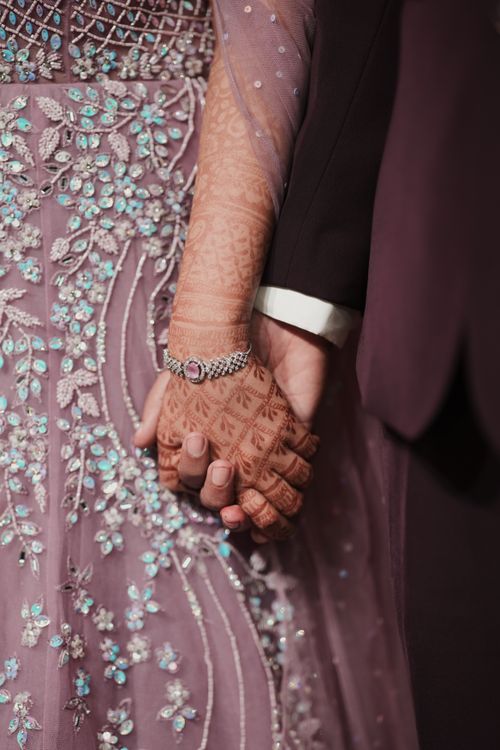 Free A close-up of a couple holding hands, adorned with intricate henna and a sparkling bracelet. Stock Photo