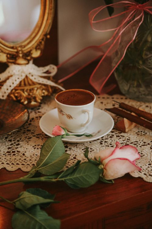 Free A chic coffee setting featuring a cup of coffee, pink rose, and lace decor, perfect for relaxation themes. Stock Photo