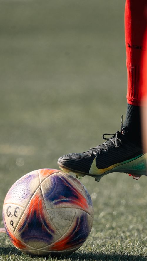 Free Close-up of a soccer player in red socks preparing to kick a multicolored ball. Stock Photo