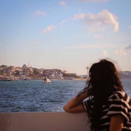 Free A woman enjoys the scenic İstanbul skyline from a ferry on a sunny day. Stock Photo