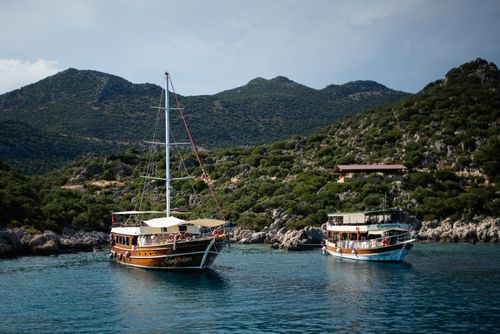 Free Two boats anchored in a tranquil cove surrounded by lush green hills under a clear sky. Stock Photo