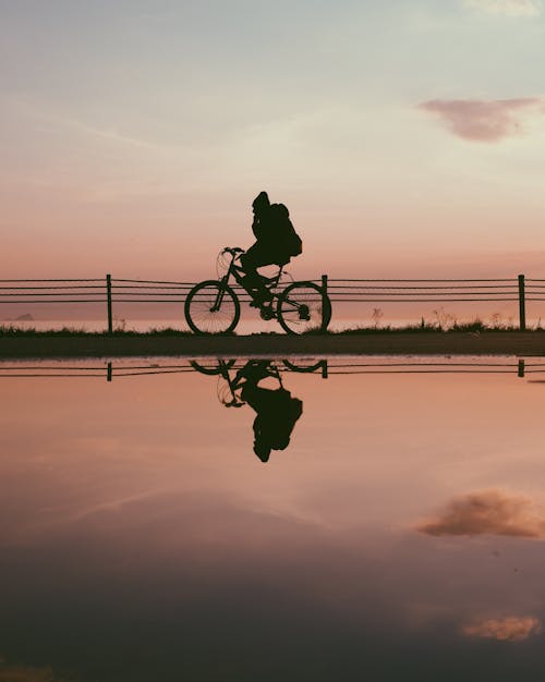 日没時に自転車に乗る男のシルエット