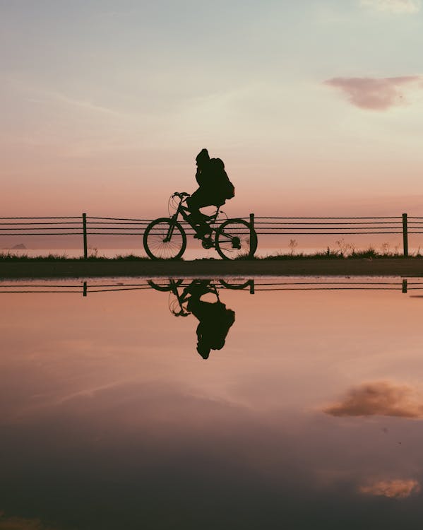 Silhueta De Homem Andando De Bicicleta Durante O Pôr Do Sol