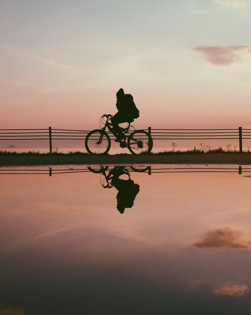Free Silhouette of a cyclist with a reflection during a tranquil İstanbul sunset. Stock Photo