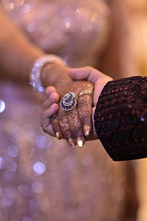 Free Elegant close-up of bride and groom's hands with intricate henna at an Indian wedding ceremony. Stock Photo