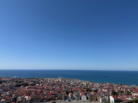 A stunning aerial view of a coastal city with clear blue skies and the ocean horizon.