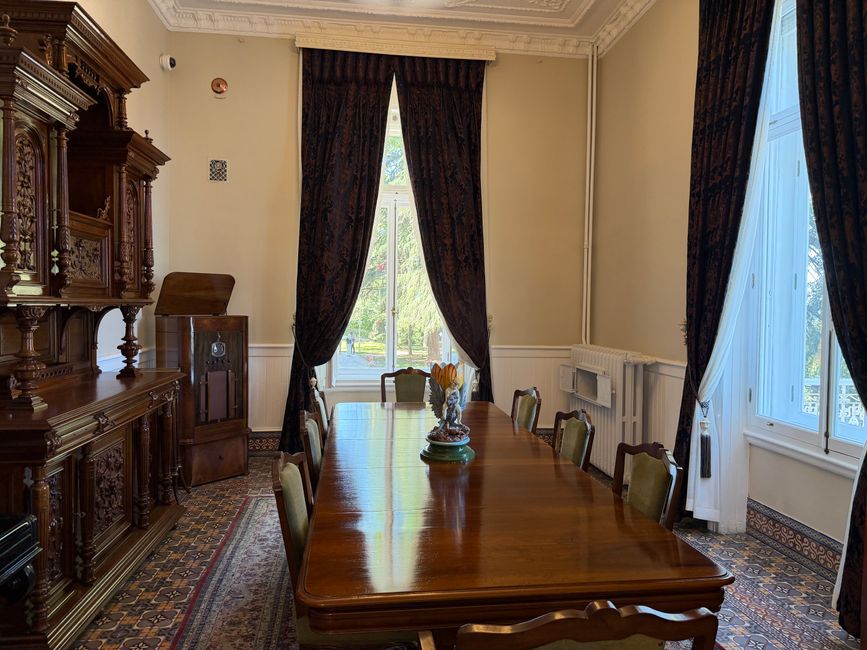 Un comedor clásico con muebles vintage, cortinas elegantes y una mesa de madera, creando una atmósfera cálida y sofisticada.