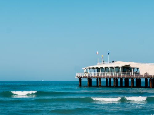 Free A tranquil image of a modern pier extending into the blue sea under a clear sky in Italy. Stock Photo