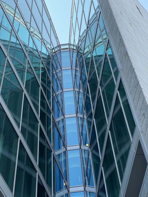 Free Upward view of a modern glass facade skyscraper in Milano, Italy, showcasing intricate reflections. Stock Photo