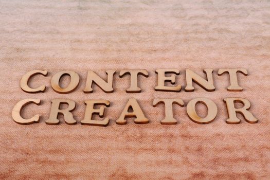 Wooden letters spelling 'Content Creator' arranged on a textured fabric background.