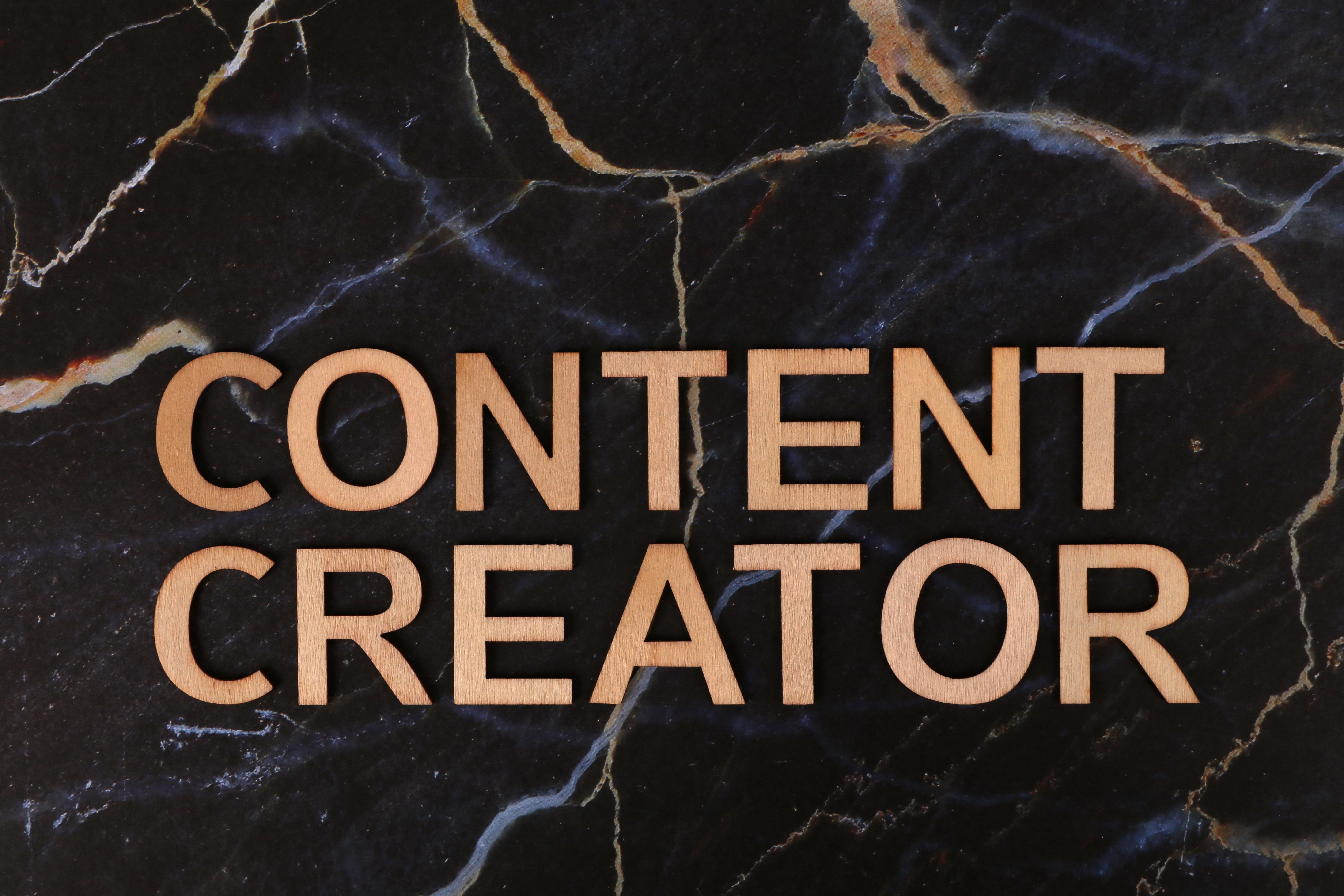 Wooden letters spelling 'CONTENT CREATOR' on a dark marble background.