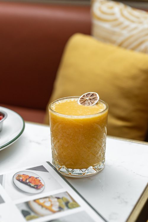 Free Close-up of a refreshing citrus mocktail with a dried orange slice on a chic, modern table at a stylish cafe. Stock Photo