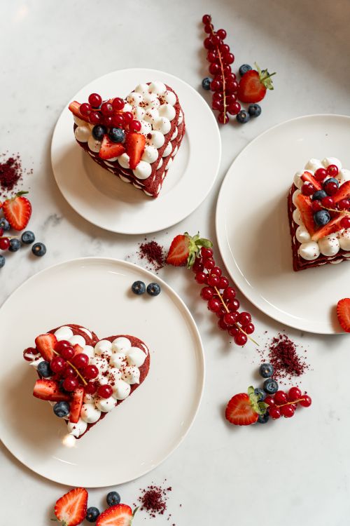 Free Decorative heart-shaped red velvet cakes with berries on a marble surface. Stock Photo