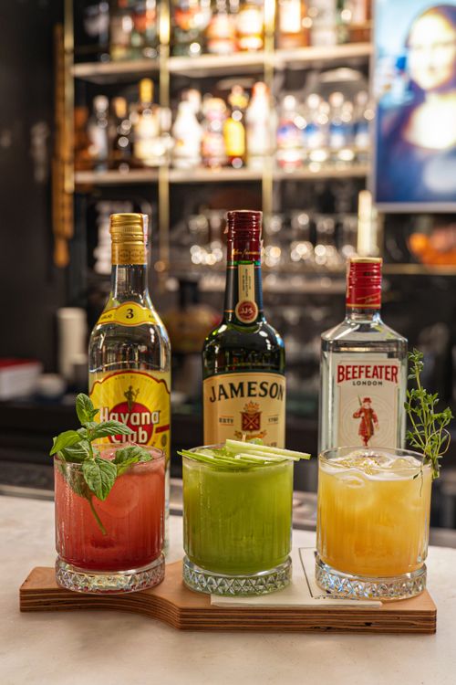 Free Vibrant cocktails with garnish displayed in a stylish bar, featuring Havana Club, Jameson, and Beefeater bottles. Stock Photo