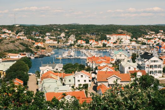 A picturesque Swedish coastal village with red and white houses, marina, and summer scenery.