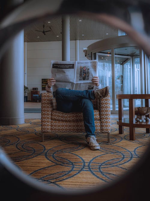 Free Man Sitting On Brown Sofa Chair Reading The Newspaper Stock Photo