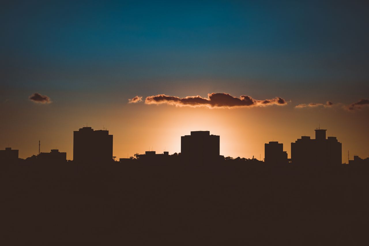 Dramatic city skyline silhouette with backlit sun during golden hour creating a stunning silhouette.