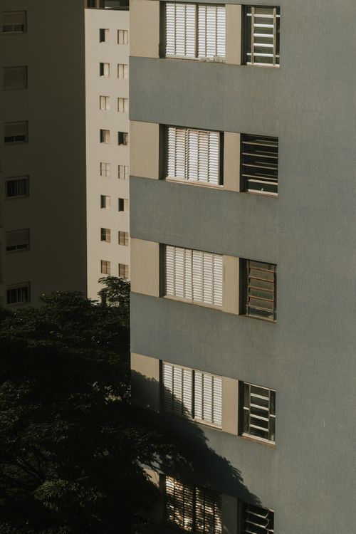 Free Sunlit facades of urban apartment buildings with striking shadows and geometric patterns. Stock Photo