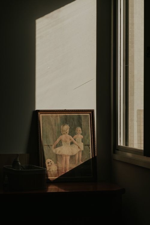 Free A serene display of a framed painting by a window, capturing gentle shadows and ambient light. Stock Photo