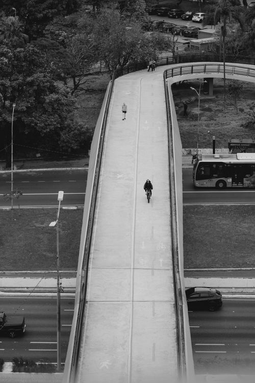 Free A monochrome view of a cyclist and pedestrian on a city bridge. Stock Photo