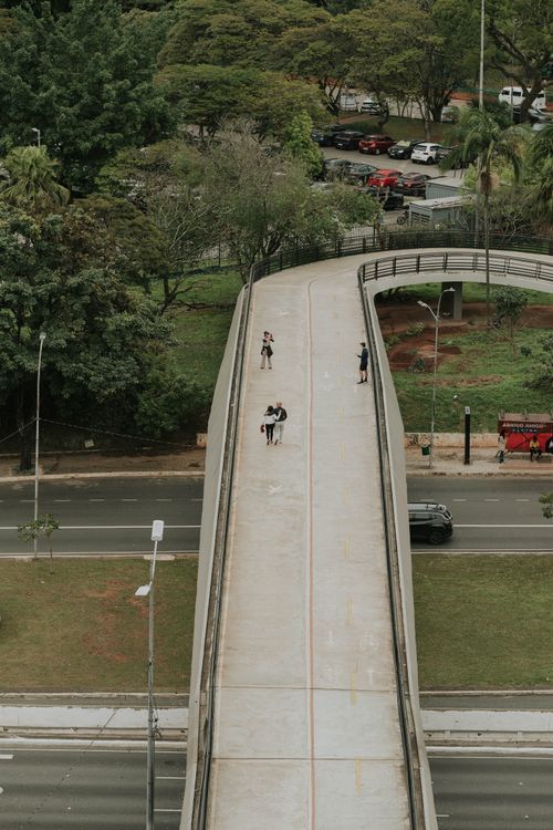 Free Overhead shot of a footbridge in a city, surrounded by greenery and a road below. Stock Photo