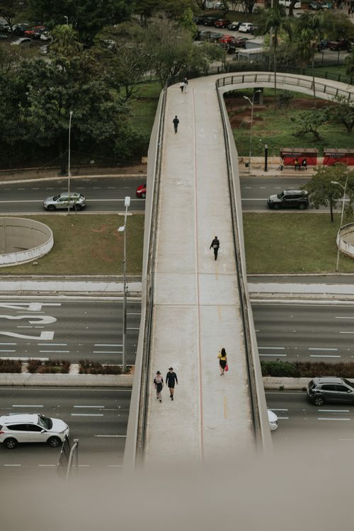 Free Aerial photo capturing people walking on a city overpass, with traffic below. Stock Photo