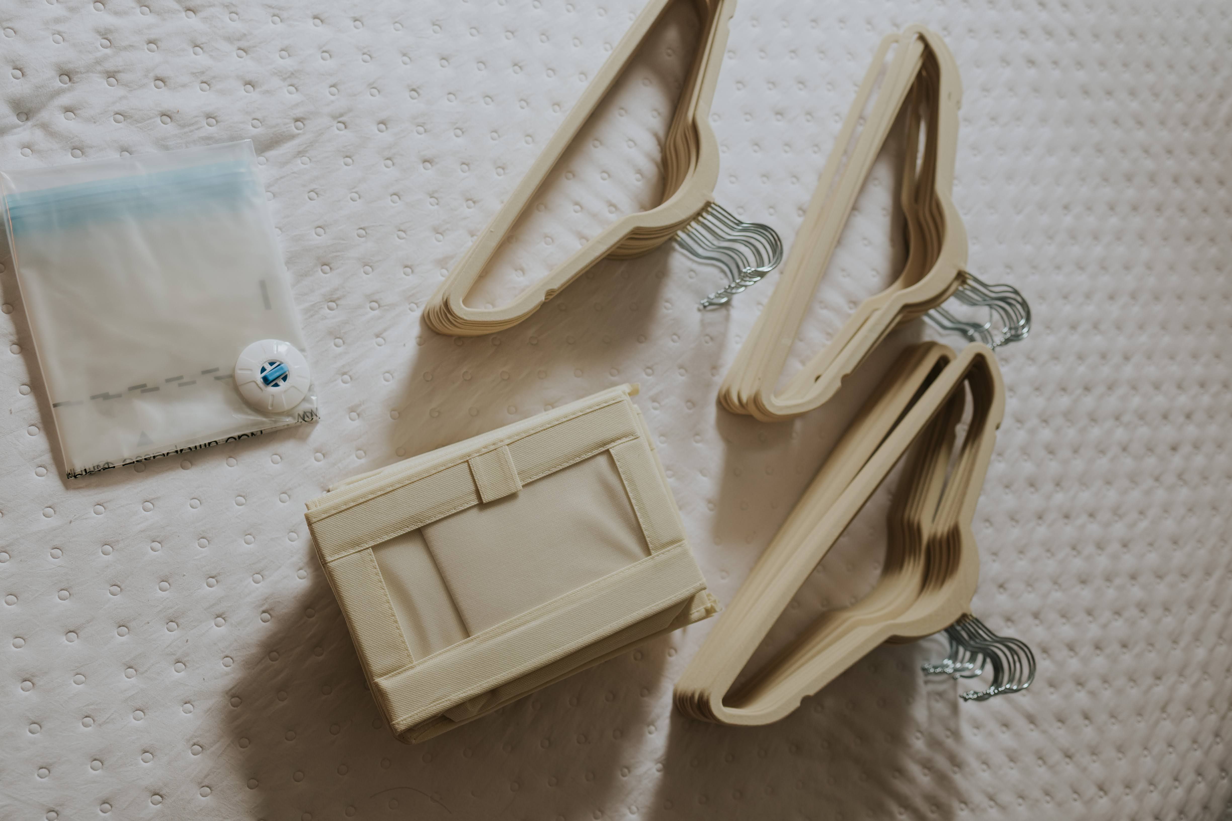 A neatly arranged flat lay of beige wooden hangers and a fabric storage box on a quilted surface.