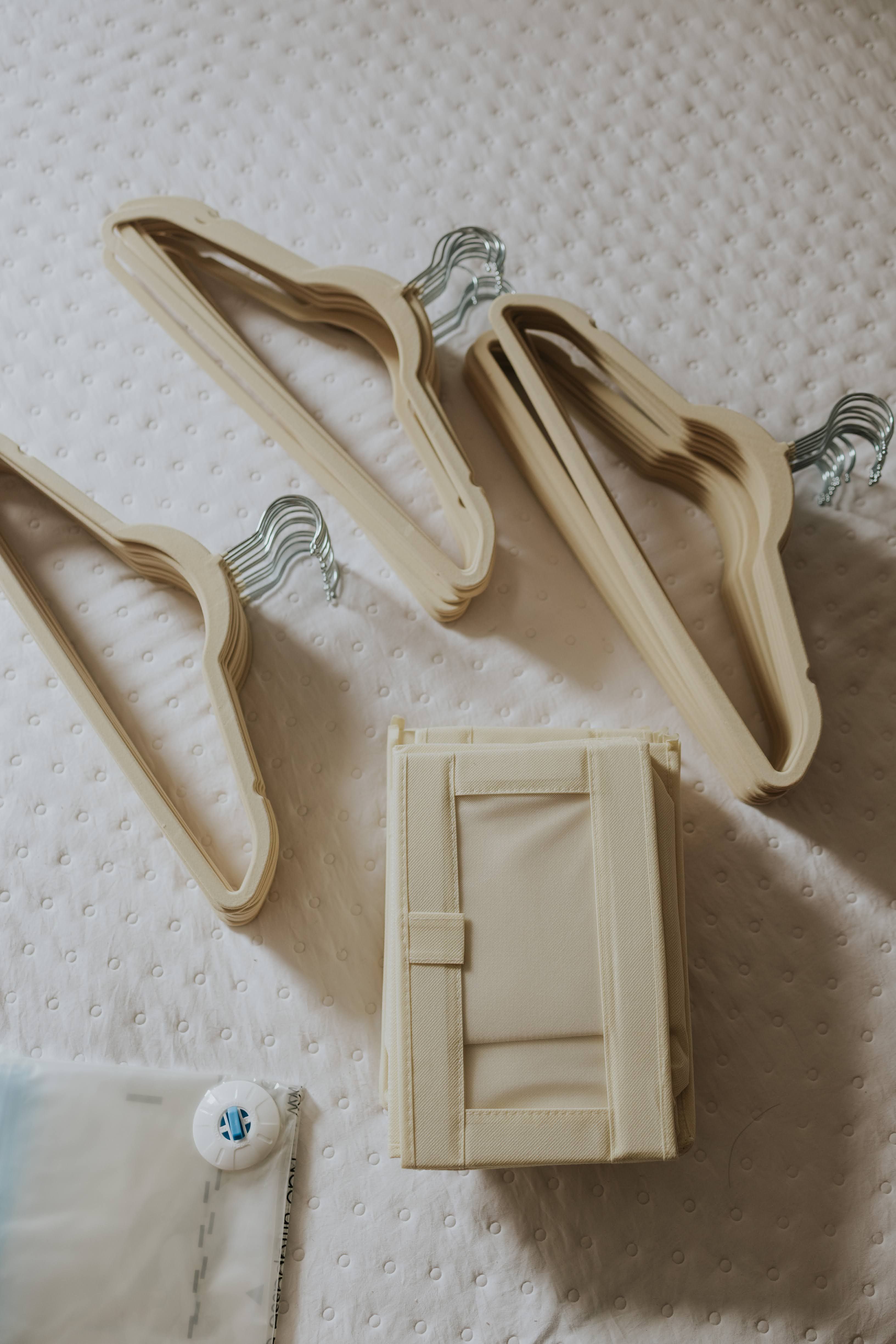 Beige velvet hangers arranged neatly on white quilted bedspread, ideal for tidy closet organization.