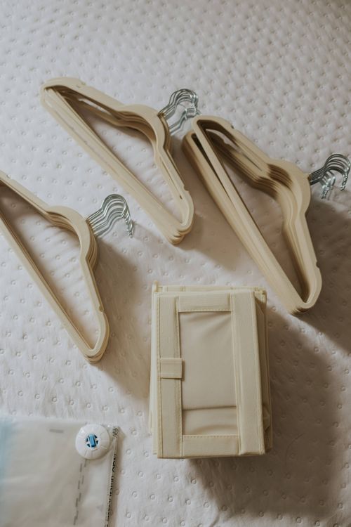 Free Beige velvet hangers arranged neatly on white quilted bedspread, ideal for tidy closet organization. Stock Photo