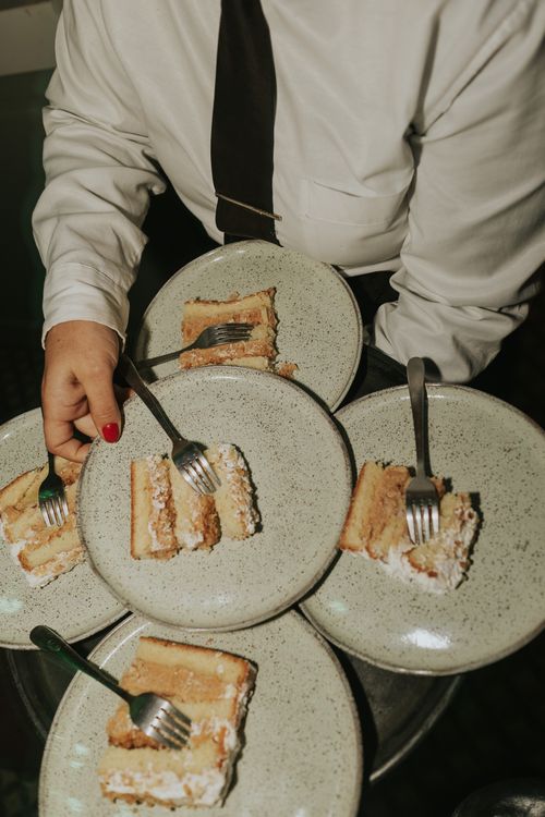 Free A waiter dressed formally serving cake slices at an event, creating a warm atmosphere. Stock Photo