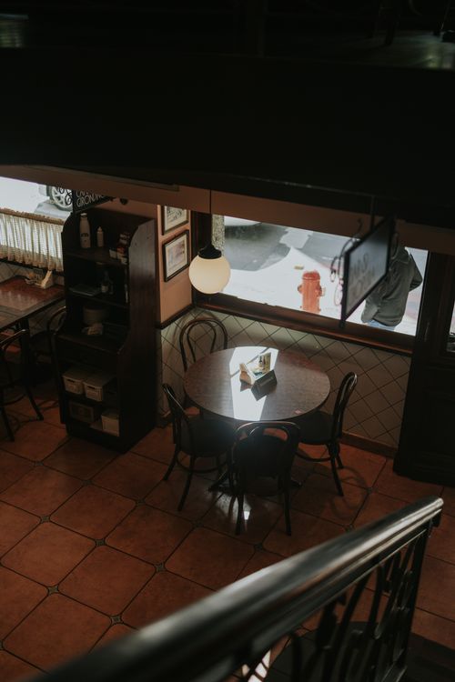 Free Warm and inviting cafe with cozy seating arrangement and natural light from the window. Stock Photo
