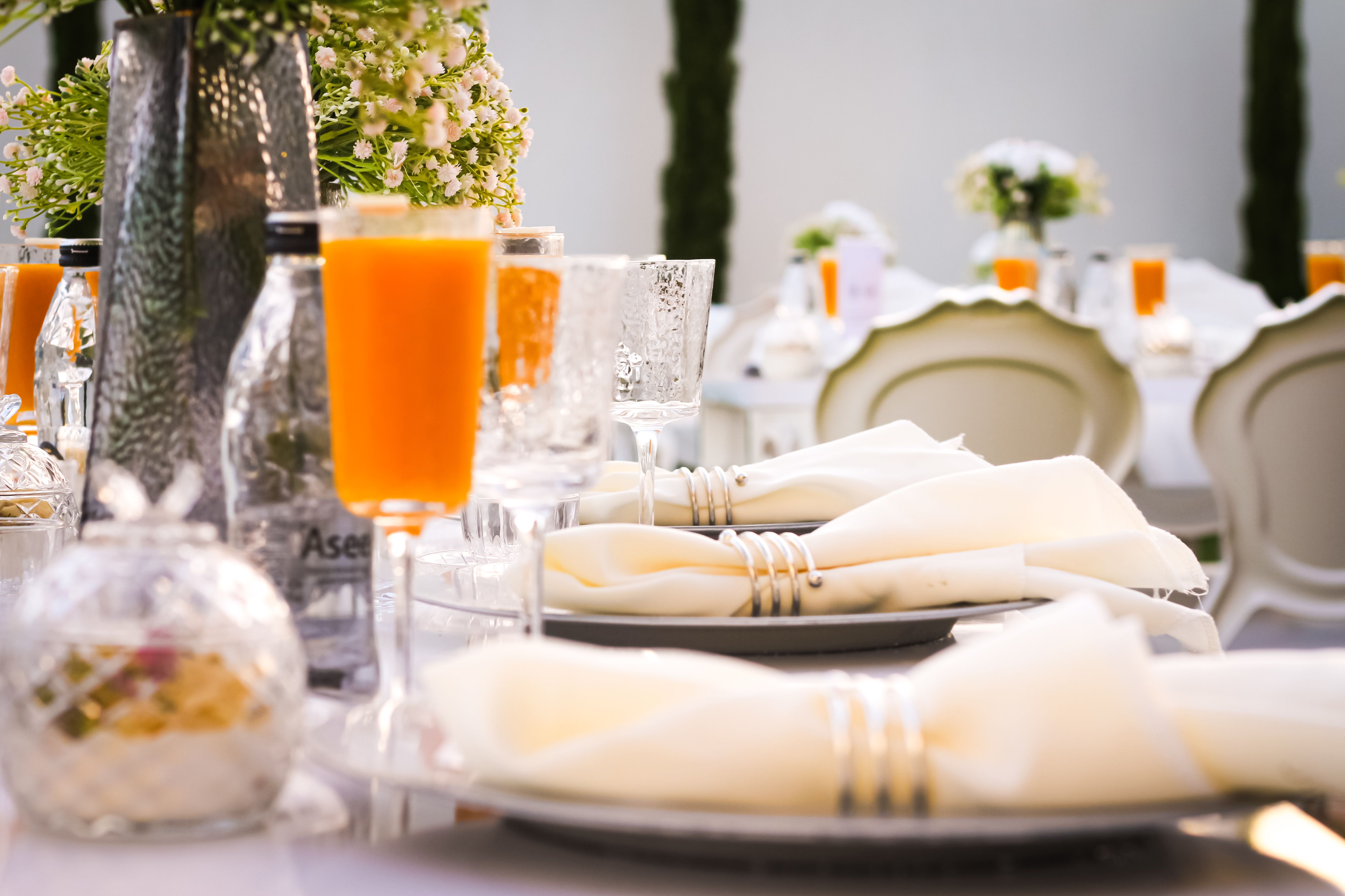 Beautifully arranged dining table with orange drinks and white decor, perfect for outdoor events.