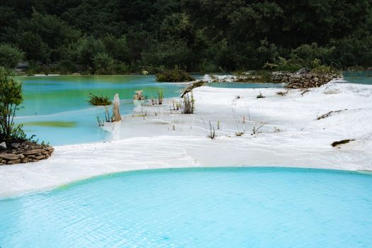 Stunning view of turquoise thermal pools surrounded by lush greenery and white deposits.