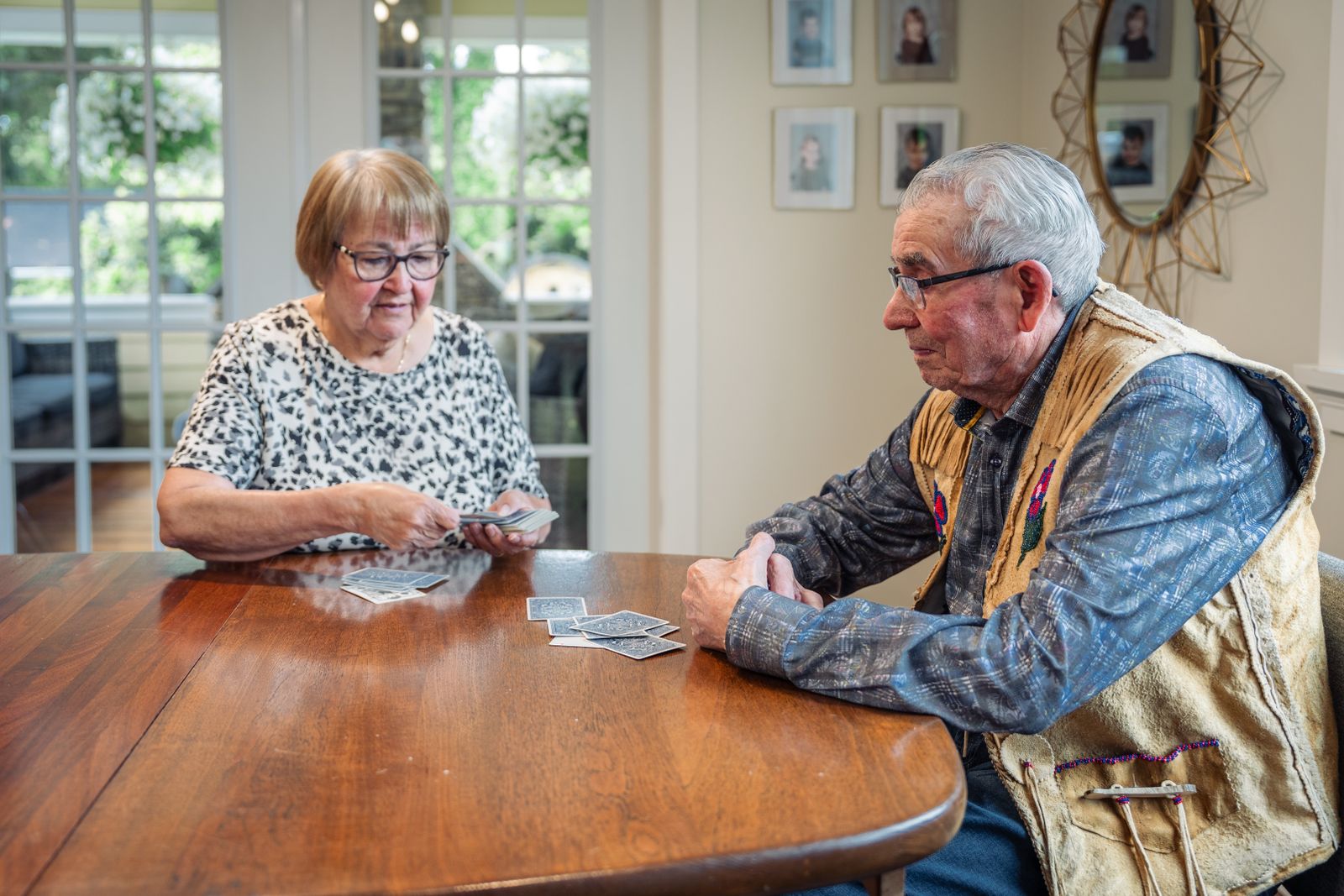 An older couple playing cards together at a wooden table