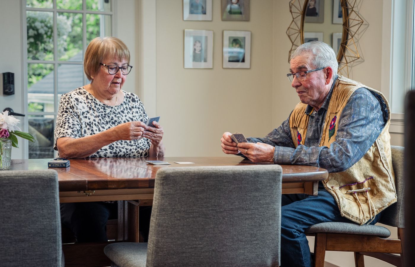 Senior couple enjoying a card game indoors, showcasing leisure and companionship.