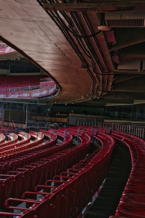 Free Explore the architectural design of an empty stadium, showcasing curved red seats and a distinctive overhead ceiling. Stock Photo