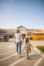 Anonymous mother leading daughter to school in city