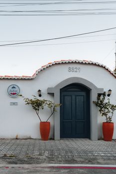 Beautiful Brazilian house facade with a blue door and orange planters, RN, Brazil.