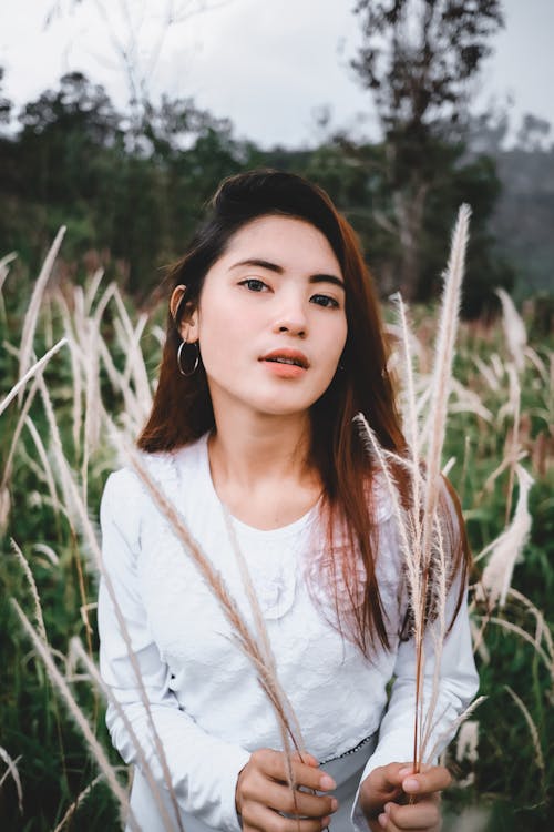 Woman In White Long Sleeve Shirt Standing On Green Grass Field