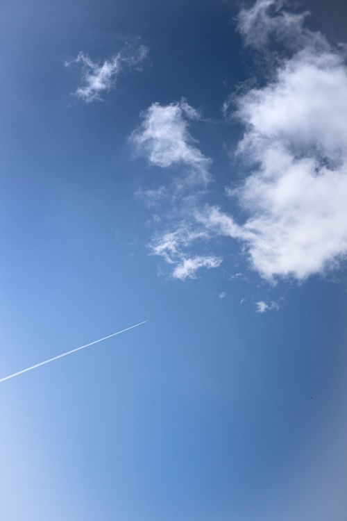 Free A bright blue sky featuring wispy clouds and a jet contrail, symbolizing travel and freedom. Stock Photo