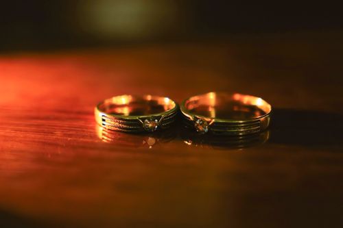 Free Two golden wedding rings with diamonds sparkle on a wooden surface, capturing romance. Stock Photo