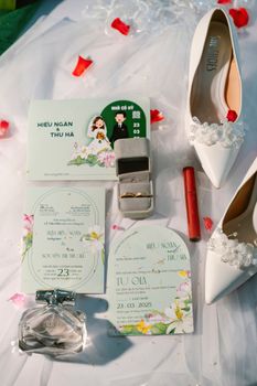 Charming flat lay of wedding invitations and accessories with floral accents in Vietnam.