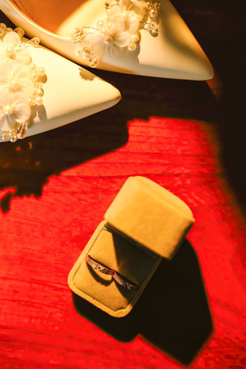 Free Elegant wedding shoes and jewelry box on a vibrant red background, exuding warmth and celebration. Stock Photo